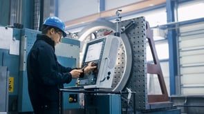 Factory worker is programming a CNC machine with a tablet computer